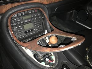 Nun lässt sich die Holzverkleidung von unten angefangen langsam lösen. Achtung: Dies geht nur, wenn der Automatikwählhebel nicht mehr vorne in P, sondern weiter hinten in N oder D steht. 