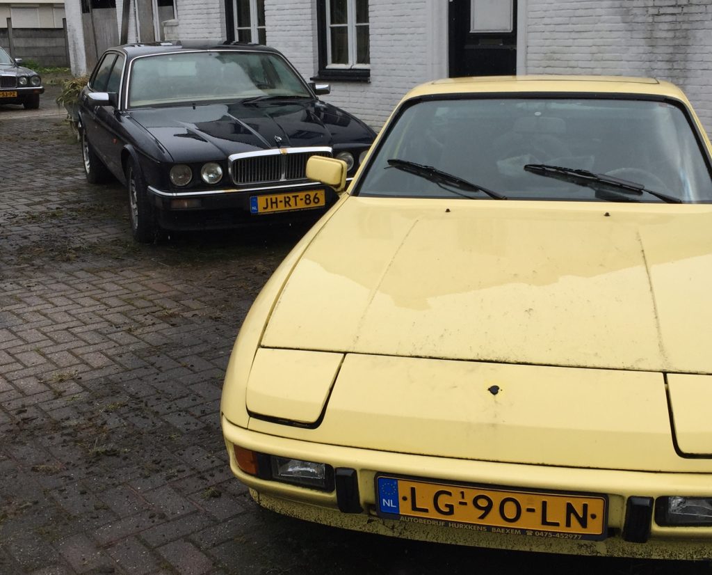 Jaguar XJ40 mit Rundscheinwerfern der späteren Serie, versteckt hinter einem zeitgenössisch gelben Porsche 924